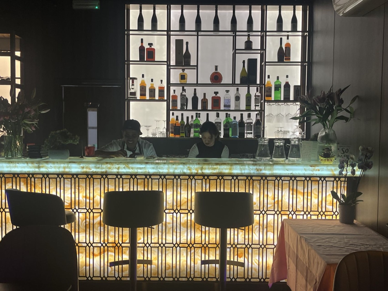 The illuminated onyx bar at Blossom, backlit shelves of spirits behind