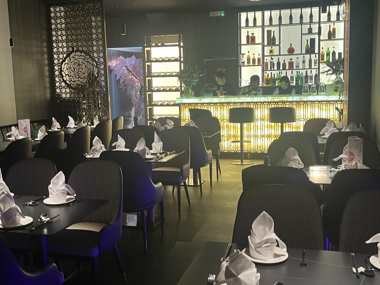 The Blossom dining room at night beneath a fibre-optic starlit ceiling, with the illuminated onyx bar glowing gold
